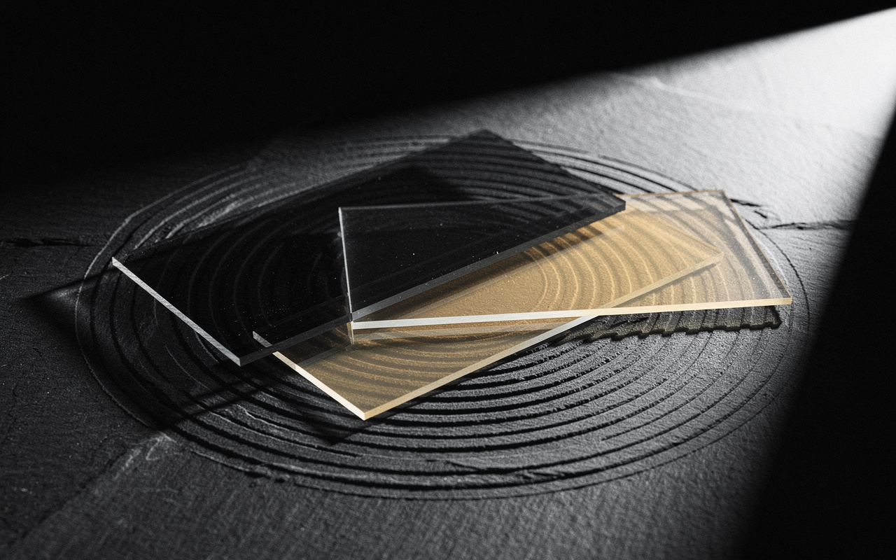 Two overlapping tinted glass filter sheets reveal concentric etched rings beneath them, lit by a raking beam, illustrating how isolating AI-driven queries works.