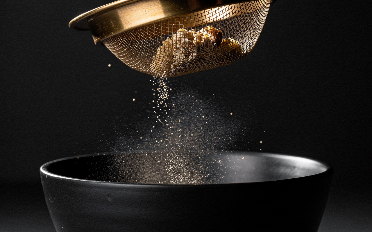 YouTube Analytics delayed data shown as glowing particles caught in a brass sieve above a dark basin.